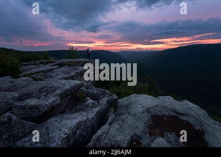 Vedute dall'alba sovrastanti da Table Rock nella Virginia Occidentale vicino alla Canaan Valley con uno zaino in spalla in posa sul bordo. Foto Stock