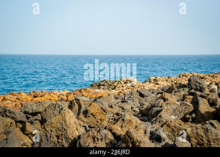 Splendida vista dalla costa rocciosa dell'Oceano Atlantico alle onde che colpiscono le scogliere rocciose sull'isola di Tenerife, Spagna sotto il cielo blu Foto Stock