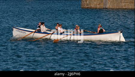 Penzance, Cornovaglia, Inghilterra, Regno Unito. 2022. I pescherecci a palangari un pilota di addestramento si gig e l'equipaggio che remano nel porto di Penzance, Cornovaglia, Regno Unito Foto Stock