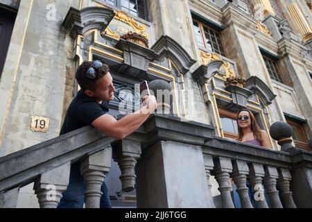 Un maschio che scatta una foto di una giovane turista femminile di fronte alla Maison Grand Place a Bruxelles, Belgio Foto Stock