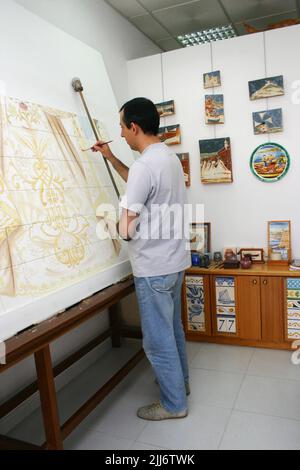 Primo piano verticale di un artista che dipinge immagini di piastrelle religiose nel suo Studio Foto Stock