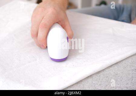 L'uomo rimuove i pelucchi utilizzando un rasoio con lanugine. Foto Stock