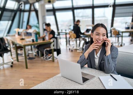Giovane donna asiatica felice di affari che indossa il vestito che lavora in grande ufficio moderno. Foto Stock