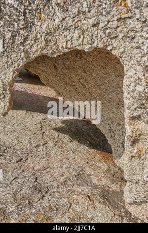 Primo piano di roccia ruvida con profonde crepe, buchi e fessure da vento, calore o erosione di acqua da riscaldamento globale o cambiamento climatico. Dettagli texture e. Foto Stock