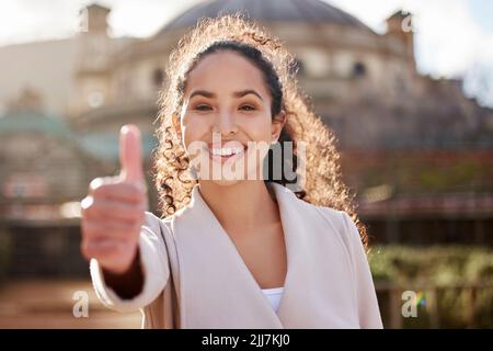 Malati sempre indietro istruzione. Ritratto di una giovane e attraente studentessa universitaria che dà i pollici in piedi fuori dal campus. Foto Stock