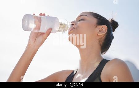 Bevete più acqua, il vostro corpo vi ringrazierà per questo. Una giovane donna che beve acqua dopo essersi allenata in natura. Foto Stock