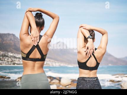 Il modo in cui si scalda è importante. Dietro l'inquadratura di due giovani donne atletiche irriconoscibili che si riscaldano prima di un'adirata sulla spiaggia. Foto Stock