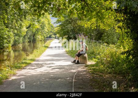 Llangollen Wales regno unito Luglio 16 2022 escursionista maschile che riposa su un sedile in pietra accanto al canale llangollen galles Foto Stock