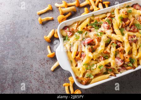 Macaroni con formaggio, pancetta e funghi in una teglia in ceramica sul tavolo. Vista dall'alto orizzontale Foto Stock