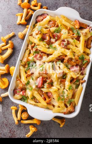 Penne casseruola di pasta con funghi di chanterelle, carne e formaggio primo piano in una teglia da forno sul tavolo. Vista dall'alto verticale Foto Stock