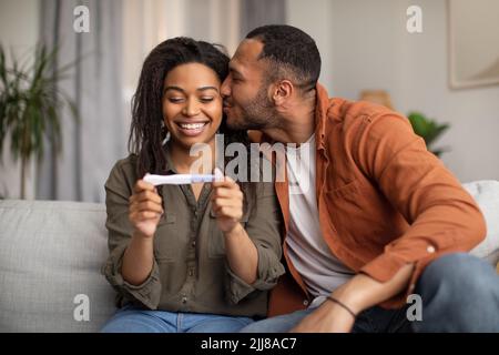 Happy African American Couple Holding Positive Pregnancy Test in Home Foto Stock