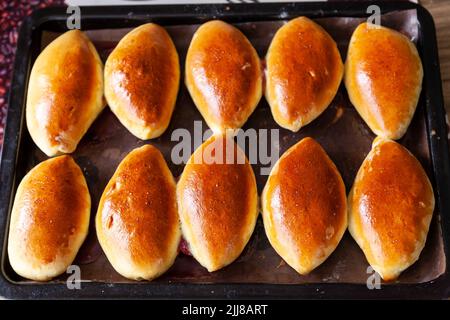 Piroski di carne russa. Mini torte tradizionali a mano su sfondo di legno. Stile rustico, vista da primo piano. Le polpette tradizionali russe di solito fatte dal nonno Foto Stock