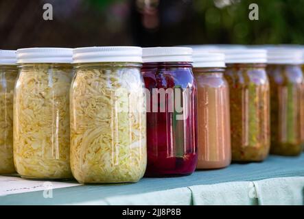 Lattine di pinta di Sauerkraut, barbabietole, e altri alimenti conservati in scatola in casa in un mercato agricolo locale Foto Stock