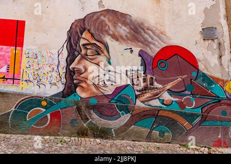 Un murale colorato raffigurante un volto femminile e una nave su una parete della casa nella città di Coimbra, Portogallo Foto Stock