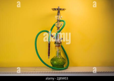 shisha hookah con fiasca di vetro e ciotola di metallo con fumo colorato su sfondo giallo. Tradizionale vacanza orientale per il relax Foto Stock