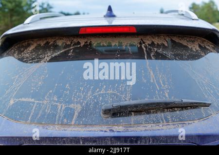Vetro sporco per auto con tergicristallo e terza luce di stop, lunotto coperto da uno strato di polvere. Foto Stock