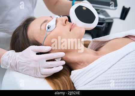 Signora sorridente in un centro medico che subisce una procedura di fotorejuvenation Foto Stock