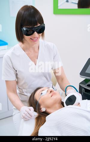 Paziente femminile in centro di cosmetologia subisce la procedura di ringiovanimento della pelle del collo Foto Stock