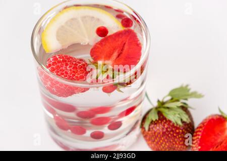 Cocktail estivo rinfrescante con fragole, frutti di bosco, limone e ghiaccio, vista laterale. Foto Stock