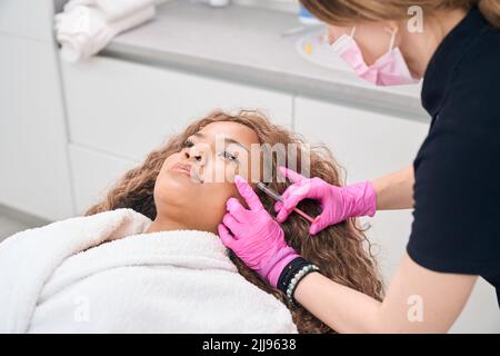 La donna riceve iniezioni di tossina botulinica in clinica di medicina estetica Foto Stock