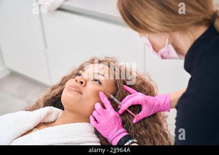 Medico di medicina estetica fa iniezioni di tossina botulinica Foto Stock