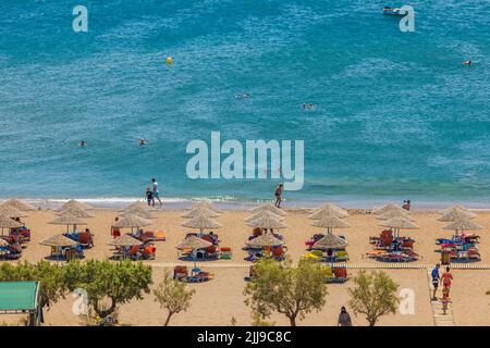 Splendida vista sulle persone che si rilassano sulla spiaggia di sabbia con lettini sull'isola nel Mediterraneo. Rodi. Grecia. Foto Stock