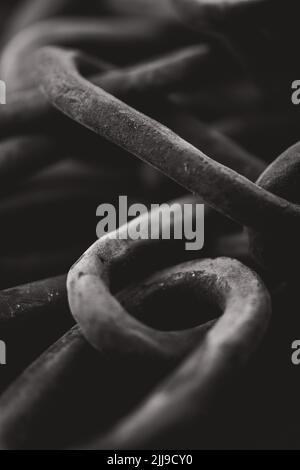 Una foto in scala di grigi di vecchie catene arrugginite Foto Stock