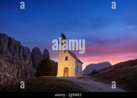 Incredibile vista sulla piccola cappella iIlluminated - Kadelle Ciapela sul Passo Gardena, Dolomiti Italiane. Tramonto colorato nelle Alpi dolomitiche, Italia. Fotografia di paesaggio Foto Stock