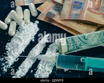 Soldi e droghe su un tavolo di vetro nero. Denaro, siringa e farmaci. Foto Stock