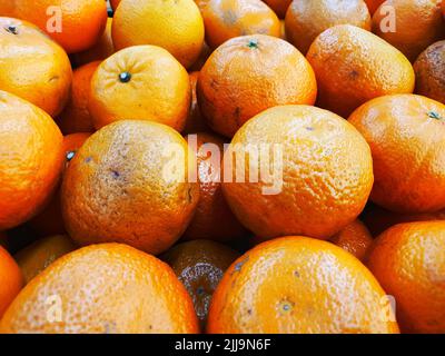 Primo piano su fresco molte arance sul mercato. Gruppo di frutta. Arance dal campo. Sfondo arancione. Foto Stock