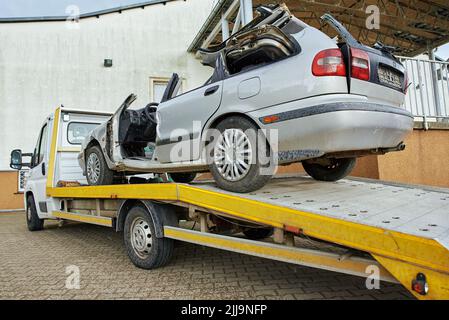 Carico di un'auto distrutta su un autocarro trainato dopo un incidente stradale, concetto di guida pericolosa dopo aver bevuto alcol, concetto di assistenza stradale Foto Stock