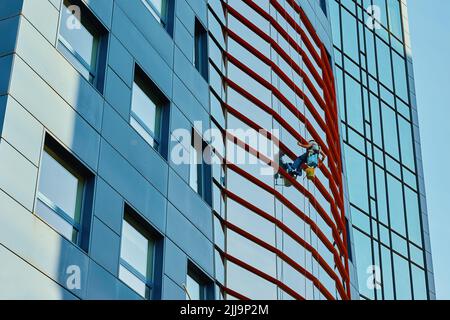 Due finestre per la pulizia dei lavoratori nel business center, gli alpinisti industriali lavano l'esterno del grattacielo, lavori rischiosi pericolosi in altezza, servizio di pulizia Foto Stock