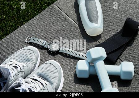 Articoli sportivi, orologi sportivi e sneaker da running su sfondo grigio, set di oggetti per esercizi all'aperto, stile di vita sano e concetto di cura del corpo Foto Stock