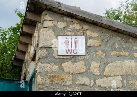 Segno wc porta vecchio cuore di pietra all'aperto legno vintage legno, concetto retrò albero in sole e servizi igienici, finestra storica. Europa Campagna Foto Stock