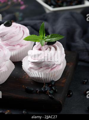 Marshmallows di frutta porzionato in una tazza di carta su un bordo di legno nero, dessert delizioso Foto Stock