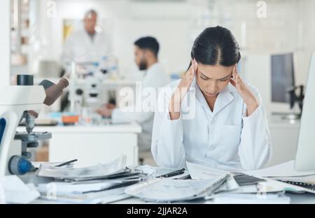 Im sicuramente non fare nuove scoperte oggi. Un giovane scienziato che guarda stressato mentre lavora in un laboratorio. Foto Stock