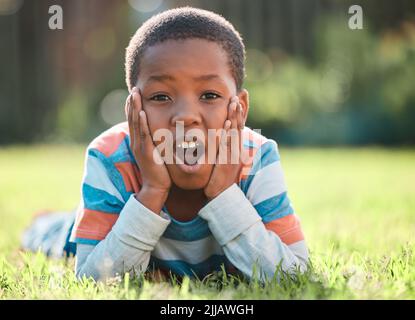 Non me lo aspettavo, un ragazzo sdraiato sull'erba fuori. Foto Stock