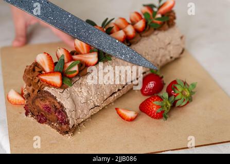 Donna mani taglio rullo. Donna taglio torta al cioccolato. Foto Stock