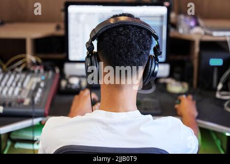 Produrre un'altra banca. Dietro l'immagine di un irriconoscibile produttore di musica maschile che lavora al suo mix in ufficio. Foto Stock