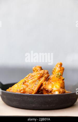 Ali di pollo fritte in una ciotola di ceramica nera Foto Stock