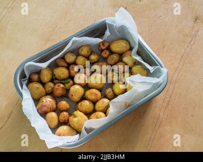 Patate intere giovani con verdure nella teglia da forno Foto Stock