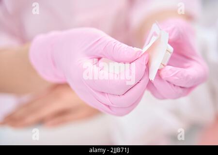 Le mani del medico in guanti sterili tengono l'anello per il piercing professionale Foto Stock