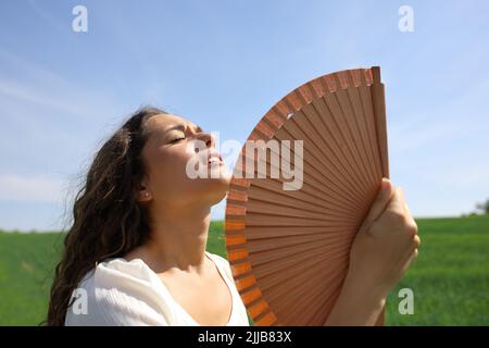 Donna stressata che soffia colpo di calore in un campo in vacanza estiva Foto Stock