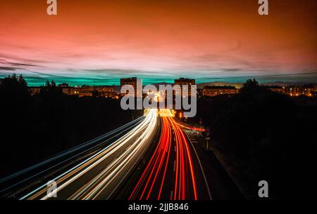 Raggi di luci, in slow motion, di auto che guidano sull'autostrada di notte per entrare e lasciare la città di Granollers, Barcellona. Foto Stock