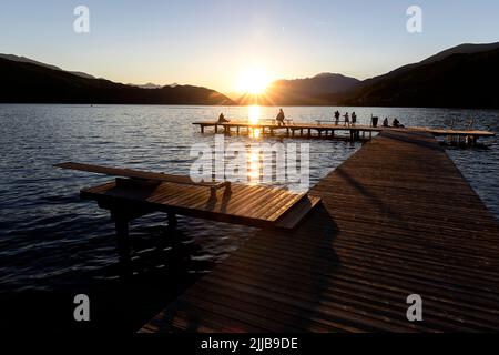 Gli abitanti del luogo si godono alla fine della bella giornata estiva su un molo in legno a Millstätter vedere il lago in Carinzia, Austria Foto Stock