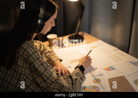 Consulente aziendale che lavora di notte su questioni di investimento a casa, studente che analizza il bilancio della società rapporto con documenti grafici Foto Stock