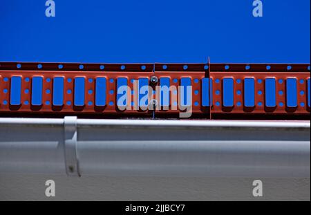 protezione in lamiera rossa che si trova sul bordo di alcuni tetti Foto Stock