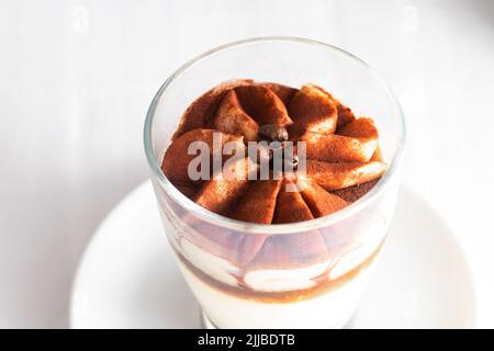 Primo piano della torta di tiramisù classica in un bicchiere su sfondo di cemento. Foto Stock