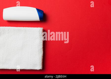 Boccetta per shampoo cosmetico con asciugamani su un tavolo colorato. Sfondo bagno, accessori per la cura delle mani e del corpo. Foto Stock