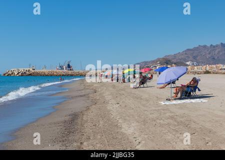 Nuotatori e bagnanti del sole godendo del tempo soleggiato e delle alte temperature sulla spiaggia di vera Garrucha, provincia di Almeria, Andalucía, Spagna Foto Stock